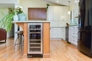 Newly installed light wood flooring in a remodeled kitchen with a wine cooler installed in the island.