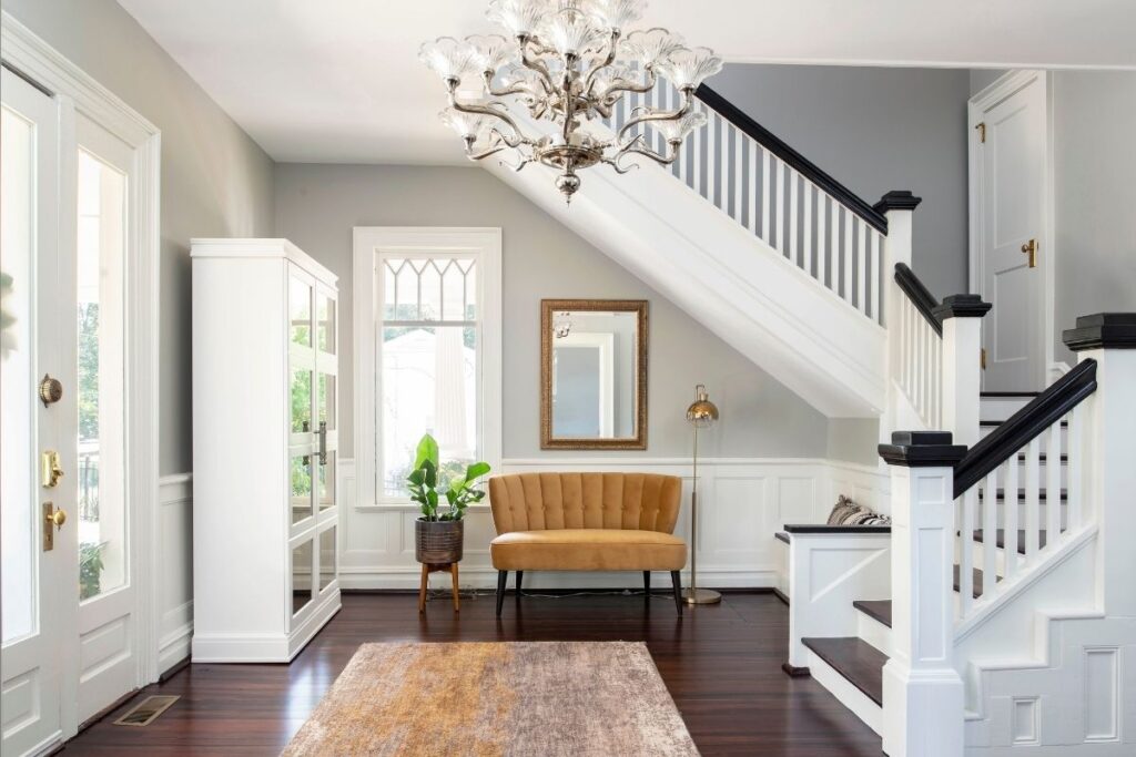 Remodeled farmhouse entryway with dark hardwood floors, light walls & staircase, and lots of natural light