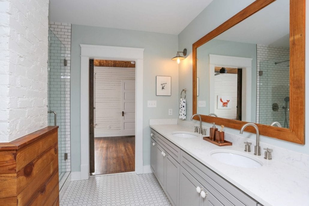 Jack-n-Jill farmhouse style bathroom with white quartz countertops and wooden accents.