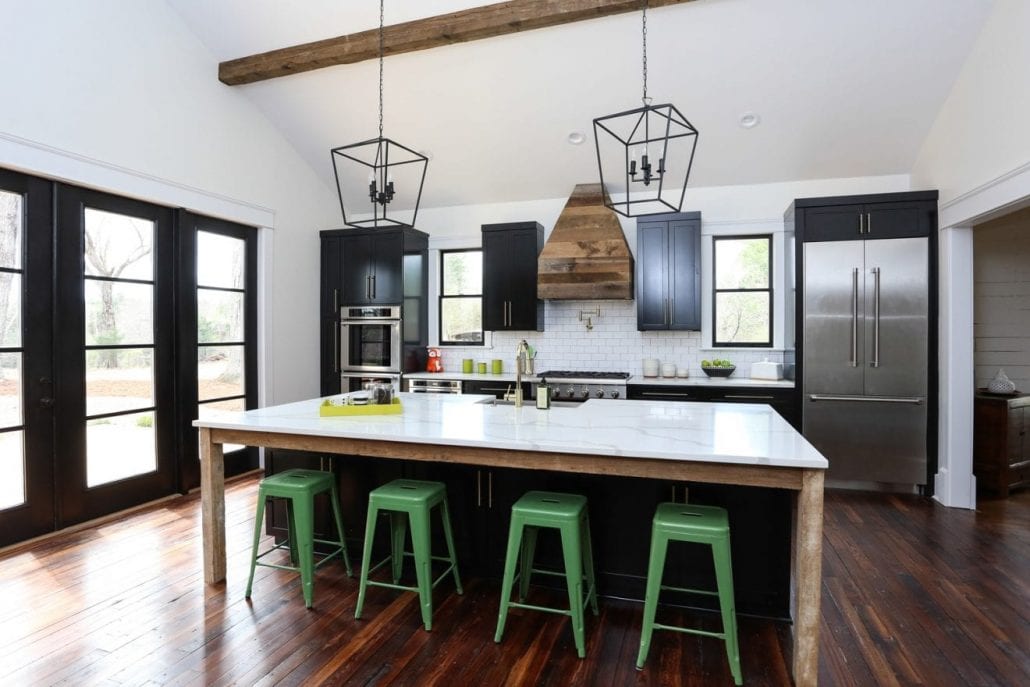 Renovated farmhouse kitchen with quartz counter-tops, pine hardwood floors and a wooden range hood cover.