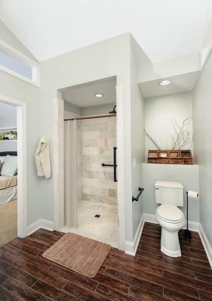 Small bathroom with walk in shower and wood-like tile on the floor.